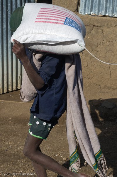 20120403_083553 Nikon D3S (1) 2x3.jpg - Man carrying US AID bag of wheat